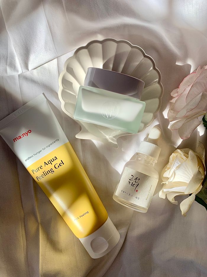 Stylized skincare products arrangement with soft lighting and flowers.