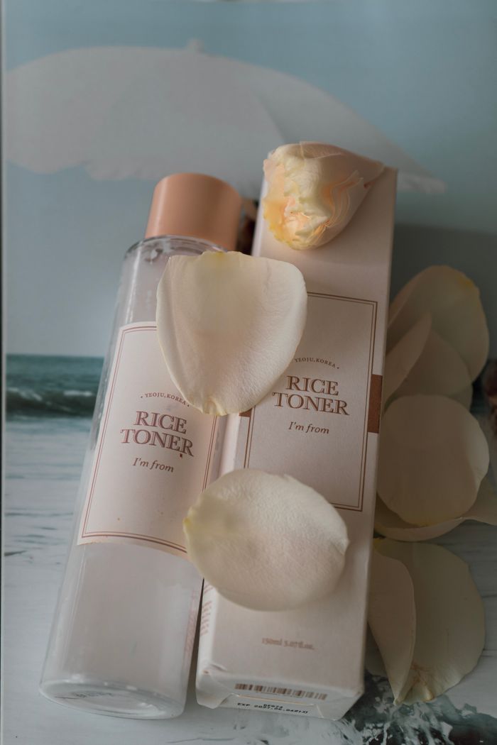 Minimalist photo of rice toner with soft rose petals, perfect for beauty promotions.